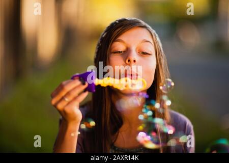Preteen girl blows bubbles with a bubble wand. Stock Photo