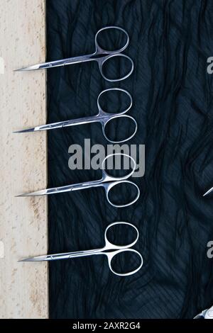 A set of cosmetic tools for manicure and pedicure stand on a black background. scissors and tongs. Stock Photo