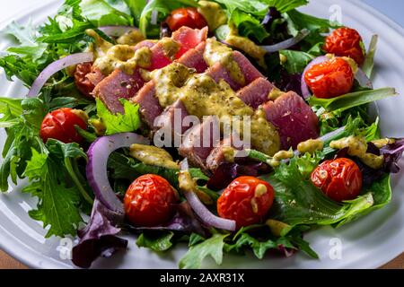 Sliced grilled Tuna steak on top of salad greens. Stock Photo