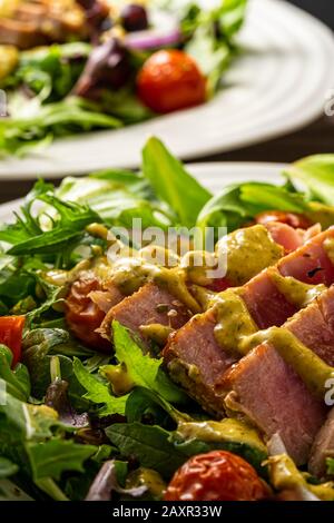 Sliced grilled Tuna steak on top of salad greens. Stock Photo