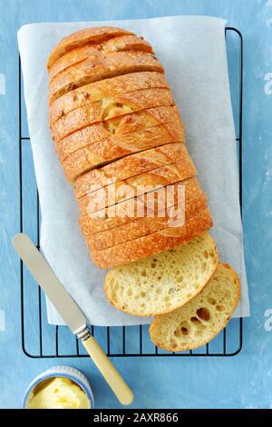 Freshly baked herb seed bread loaf in slices on blue background.  Vertical format in flay lay composition.  Shot in natural light. Stock Photo