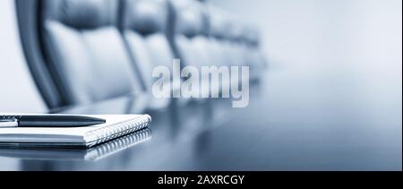 Closeup of notepad kept on table in empty conference room Stock Photo