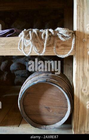 A wine barrel, a thick rope, and a purple cloth on a shelf against the stone wall in the castle storeroom. Stock Photo