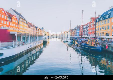 Scenic summer sunset view of Nyhavn pier with color buildings, ships, yachts and other boats in the Old Town of Copenhagen, Denmark Stock Photo