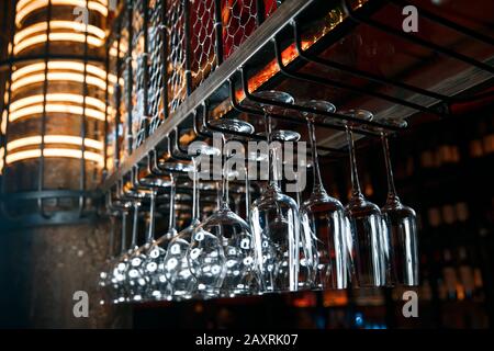 Clean glasses over the bar. Clean glasses for alcoholic beverages hang in several rows over the bar Stock Photo