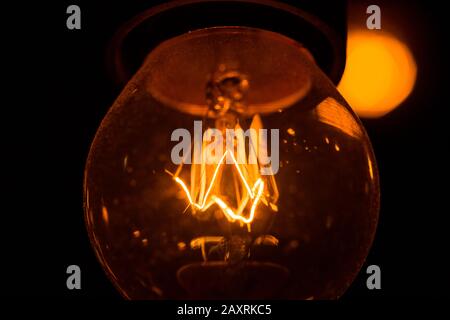One pendant burning light bulb for interior decor shine in the dark. Stock Photo