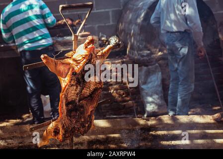 Traditional suckling pig cooked on the charcoal grill. The little pig is roasted whole on an open fire. Organic pig on the spit. Stock Photo