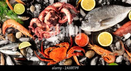 Fish and seafood variety, a flat lay top shot. Sea bream, shrimps, crab, sardines, octopus on ice with lemons and caviar Stock Photo