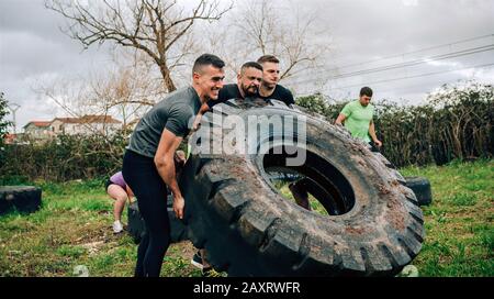 Participants in an obstacle course turning a wheel