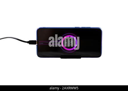 Mobile phone, smartphone being charged isolated. battery charge icon is displayed on screen, connected usb cable. Stock Photo