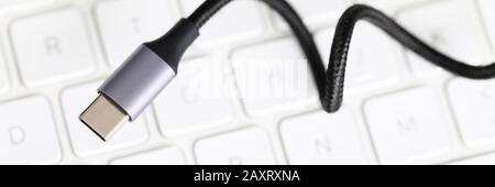 Usb type c cable against laptop keyboard background. Stock Photo