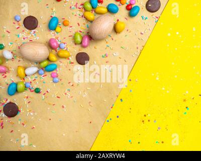 Colorful Easter eggs, sweets on yellow background, copy space Stock Photo