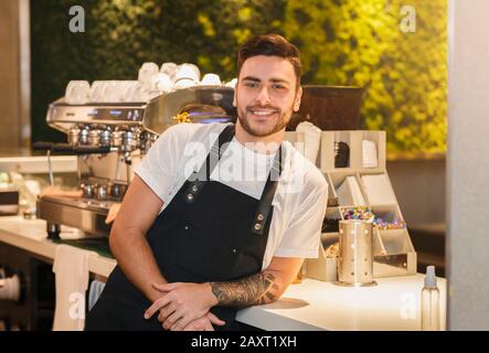 Barista Guy Posing Near Coffee-Machine Standing In Cafe Stock Photo
