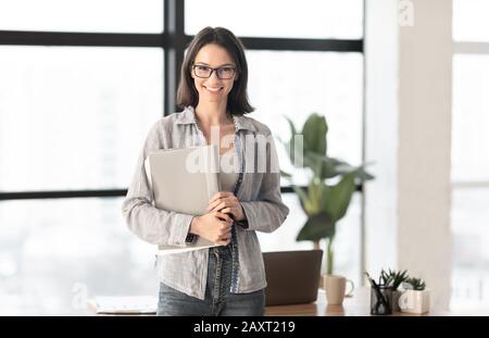 Happy manager smiling at camera in contemporary office Stock Photo