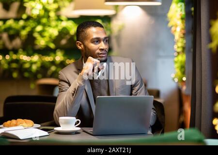 Afro manager drinking tea and using personal computer at cafe Stock Photo