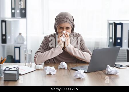 Sick employee suffering from virus but need to work, taking pills for flu and using laptop at home, copy space Stock Photo