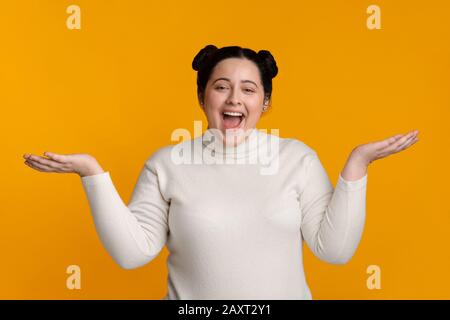 Surprised Plus Size Girl Posing With Spreaded Hands Over Yellow Background Stock Photo