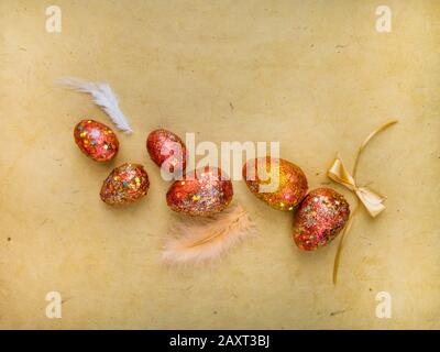 Premium gold set of golden red easter eggs painted with innovative acrylic on yellow paper background Ester concept. Top view Stock Photo