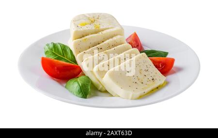 Plate with rectangular slices of mozzarella cheese, fresh basil and quarters of tomato isolated on white background. Healhy mediterranean cuisine. Stock Photo
