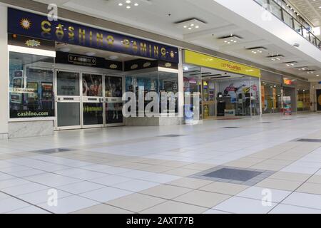 Inside a shopping mall with a betting shop, a pawn shop and an expensive furniture and electrical goods shop in a council estate Stock Photo