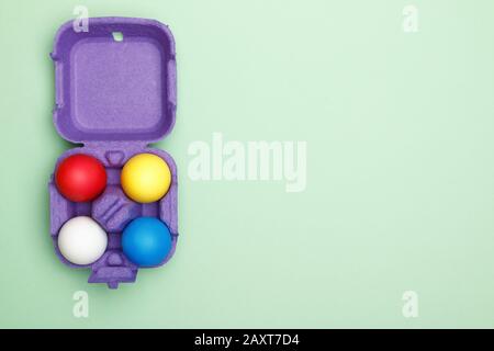 Box with colored easter eggs on a mint green background. Copy space. Stock Photo