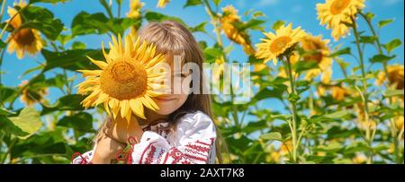 A child in a field of sunflowers in an embroidered shirt. Ukrainian. Selective focus. Stock Photo