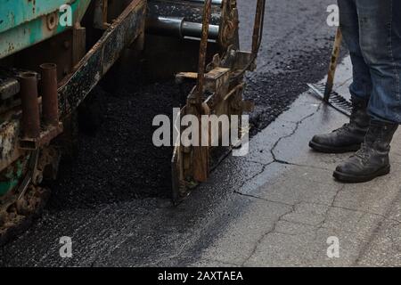 Workers using asphalt tools during road construction. Stock Photo