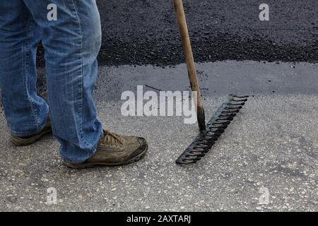 Workers using asphalt tools during road construction. Stock Photo