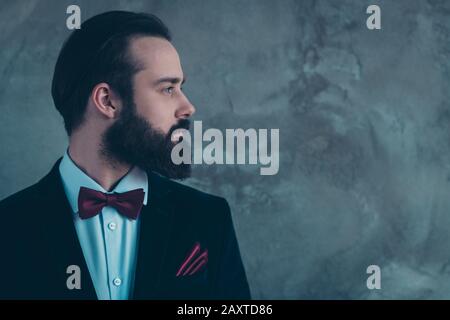 Close-up profile side view portrait of his he nice attractive bearded serious focused guy wearing tux isolated over gray concrete industrial wall Stock Photo