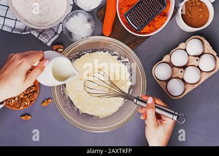 Woman's hands pouring milk into a bowl with other ingredients Stock Photo