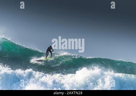 A surfer riding on the crest of a huge towering wave at Fistral in Newquay in Cornwall. Stock Photo