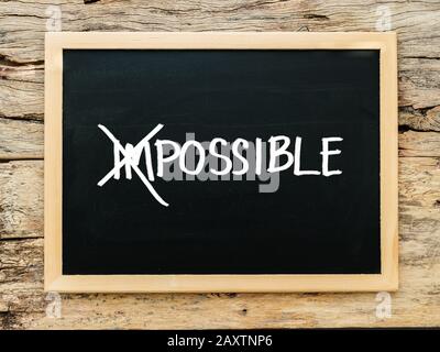 text impossible on black chalk board with cross over on 'im'. possible ,success and challenge concept. Stock Photo