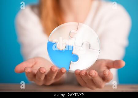 Circular object made of jigsaw puzzles over a person's fingers Stock Photo