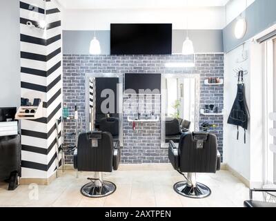 Modern bright beauty salon. Hair salon interior business with industrial minimal look. Black and white decoration with mirrors, chairs,tv screen and m Stock Photo