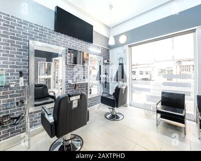 Modern bright beauty salon. Hair salon interior business with industrial minimal look. Black and white decoration with mirrors, chairs,tv screen and m Stock Photo