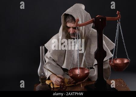 An old male monk is engaged in alchemical experiments and records their results. Stock Photo