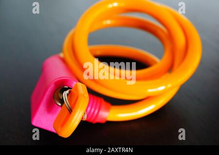 Closeup of pink and orange cable lock on a wooden table under the lights Stock Photo