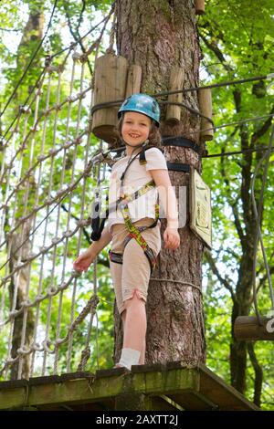Young girl girls child kid on a children obstacle course activity Trail high in woodland forest tree, at an adventure park in France during the summer. (112)