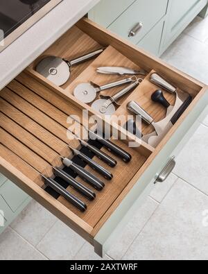 Knives and pizza cutters in open kitchen drawer Stock Photo