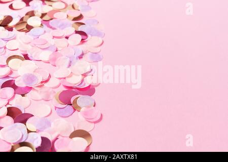 Pastel pink background with colorful round paper confetti. Holiday concept. Flat lay. Backdrop for your design. Stock Photo