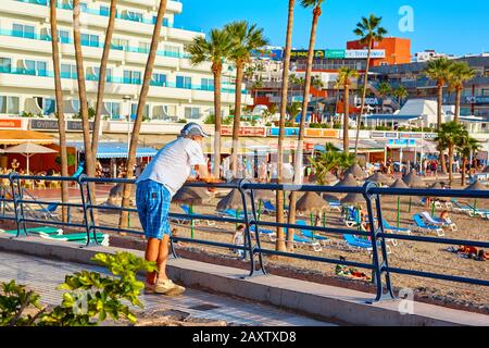 Spain, Tenerife, Adeje - December 17, 2018: Older man looks at the beach at the seaside resort. Summer sunset. Stock Photo