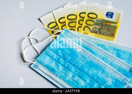 Medical masks and 200 Euro bills as a symbol of increased prices for protecting the respiratory tract from viruses. Stock Photo