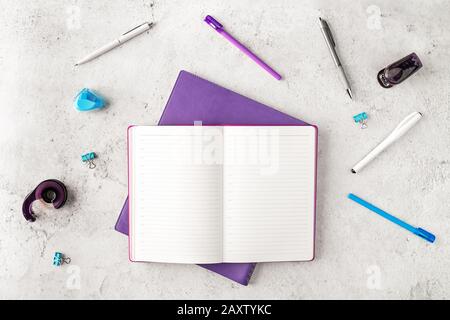 Top view of workplace with notepads, pens and other office supplies on concrete background. Opened organizer with place for text. Women's business con Stock Photo