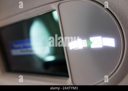 Aircraft 'Fasten seat belt / seatbelt' overhead light sign lit up & illuminated during flight in a Bombardier plane / airplane aeroplane. (112) Stock Photo