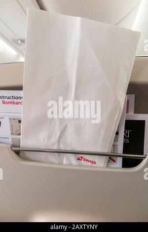 Sick / travel motion sickness bag for safe collection / holding of vomit if someone is ill, in the back of a plane seat during an airplane flight. (112) Stock Photo