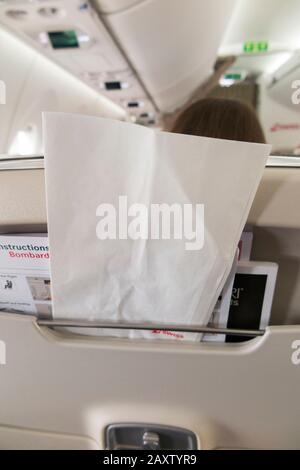 Sick / travel motion sickness bag for safe collection / holding of vomit if someone is ill, in the back of a plane seat during an airplane flight. (112) Stock Photo