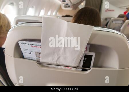 Sick / travel motion sickness bag for safe collection / holding of vomit if someone is ill, in the back of a plane seat during an airplane flight. (112) Stock Photo