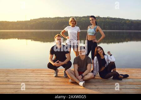 A group of athletes stands on the background of a lake in a city park. Stock Photo