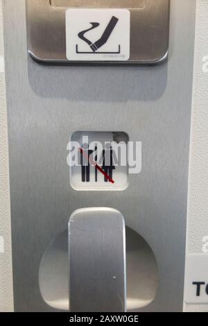 Handle on the inside of the toilet door with ash tray / ashtray and No Smoking sign, and locked / engaged symbol in loo compartment / lavatory / WC in in Bombardier C series plane / aeroplane / airplane. (112) Stock Photo