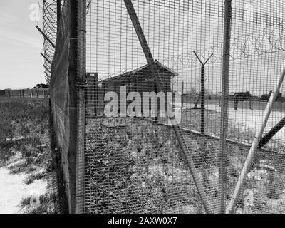 Robben Island, South Africa - 24 November 2019: Wire fence, with razor wire on top, encircles a former prison compound on Robben Island. Old buildings Stock Photo